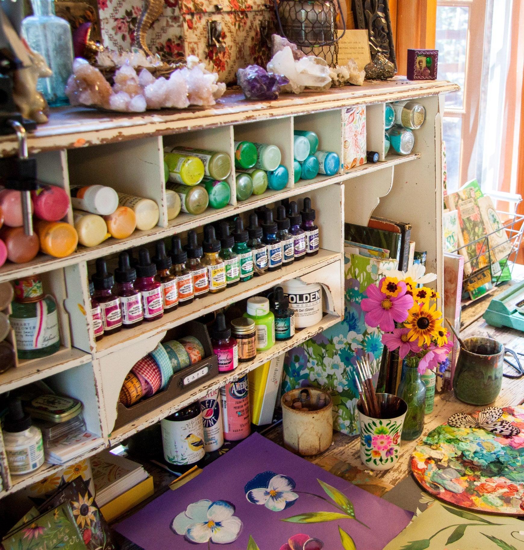 Art studio with shelves of supplies, a desk with art materials, and colorful decorations.